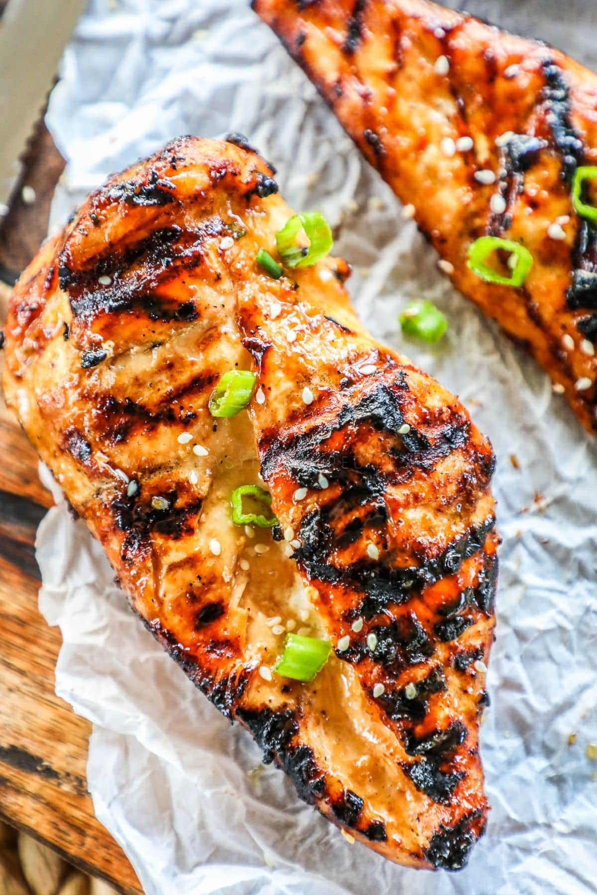teriyaki marinated grilled chicken breast on a cutting board with parchment paper