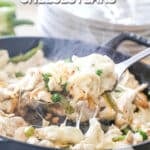 A spoon scoops the cheesy chicken for Chicken Cheesesteaks from the cast iron skillet. The text reads, "Chicken Cheesesteaks"