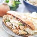A chicken cheesesteak sandwich on a white plate with potato chips on the side. The text reads, "Chicken Cheesesteaks"