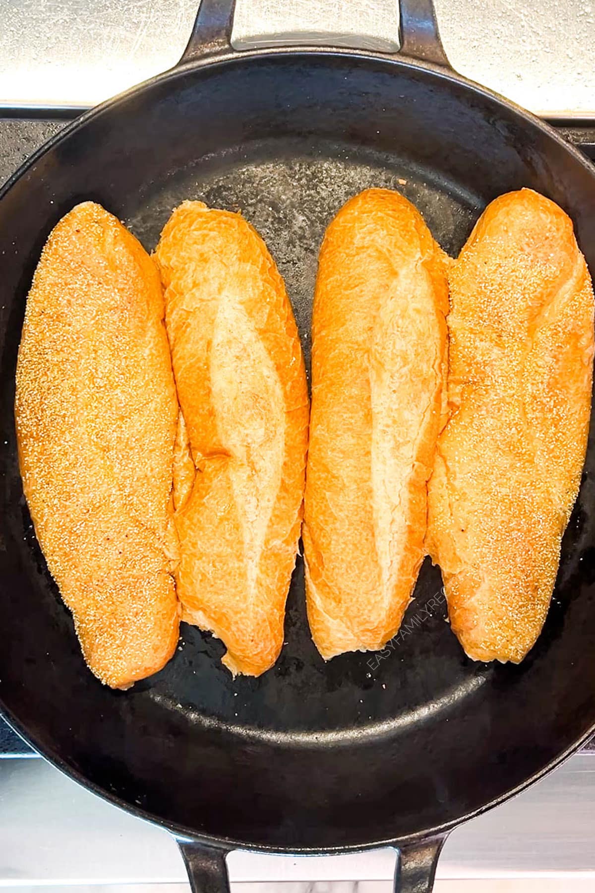 Step 1 for making chicken cheesesteak sandwiches: Toast the buns. 