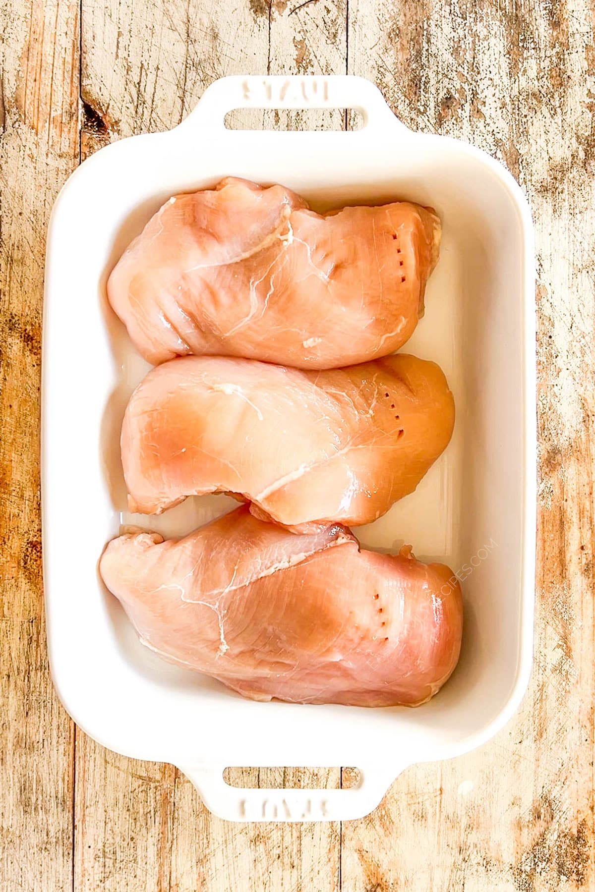 Chicken is placed in a white casserole dish for Mexican Chicken Bake