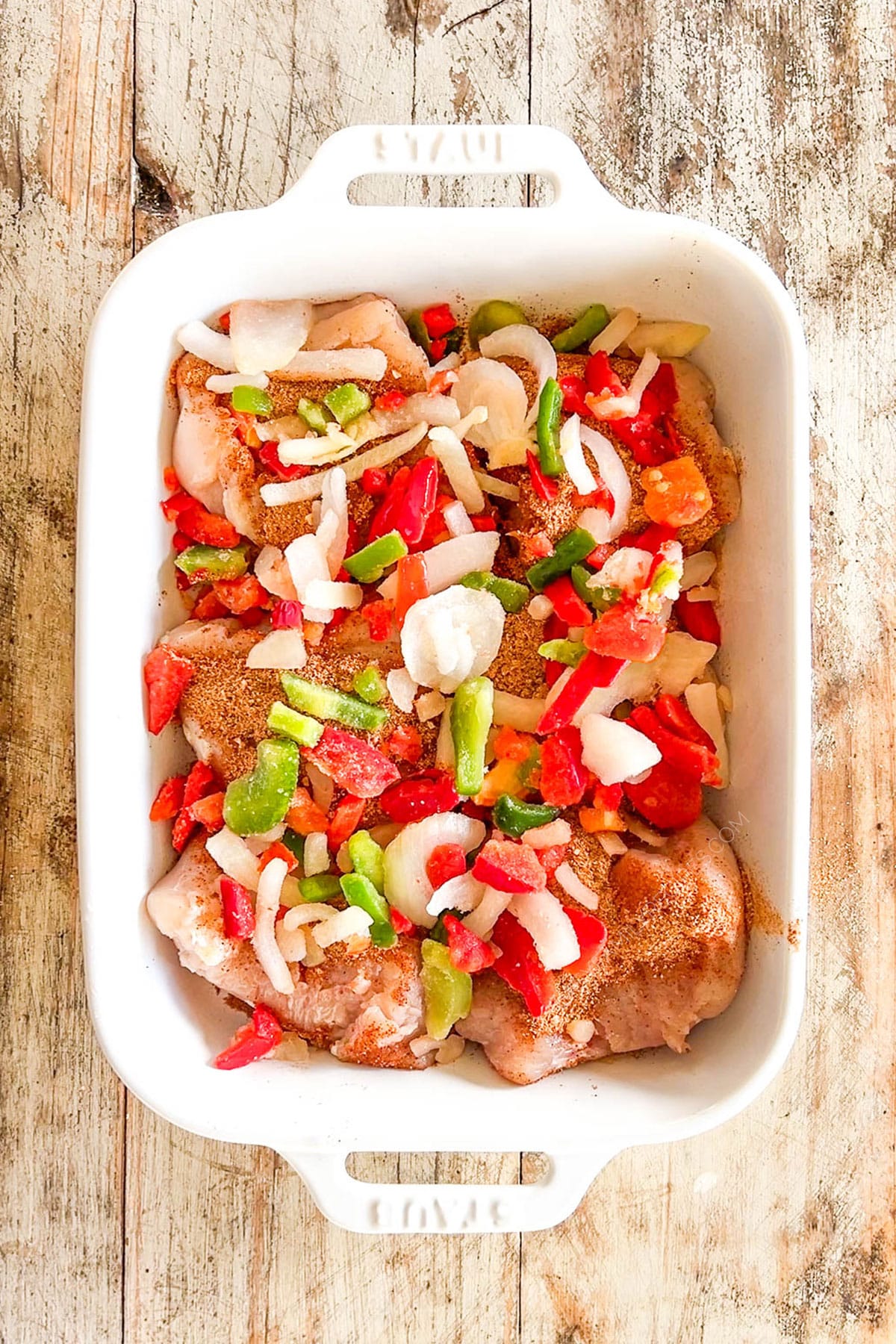 Chicken is topped with peppers and onions for Mexican Chicken Bake