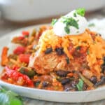 A serving of Mexican Chicken Bake with sour cream on a white plate.