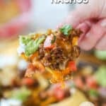 a chip loaded with ground beef and avocado, held.