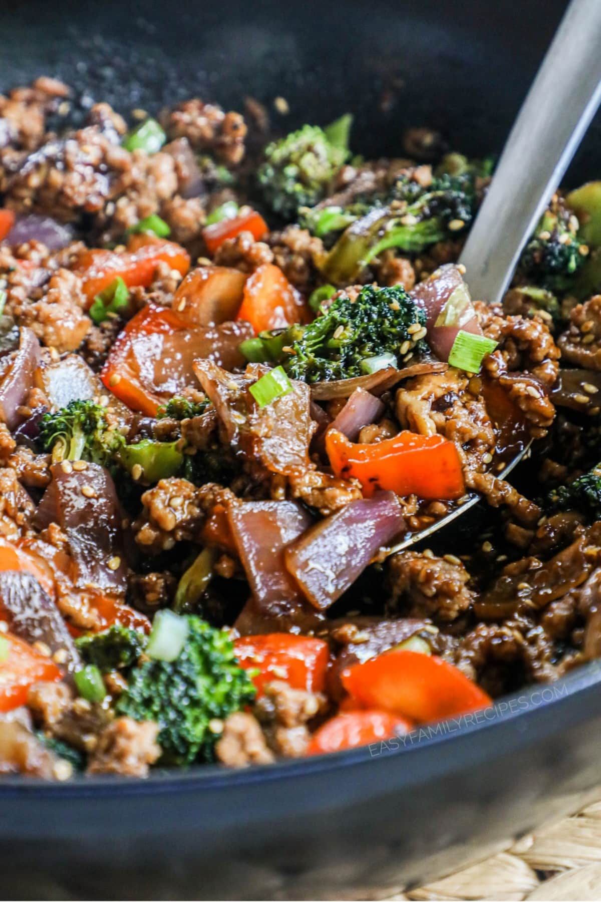 ground chicken stir fry being scooped out of a skillet