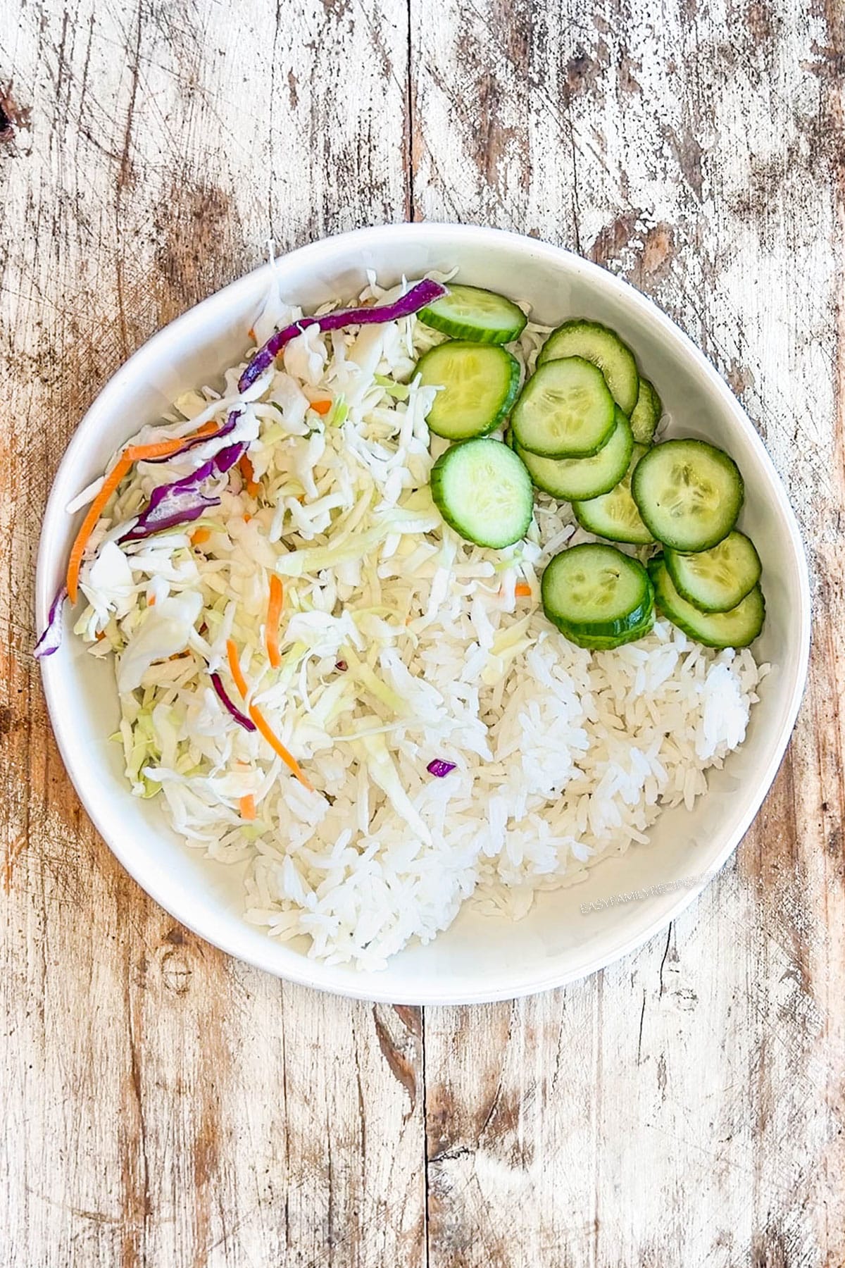 rice, cabbage, and sliced cucumber in a bowl.