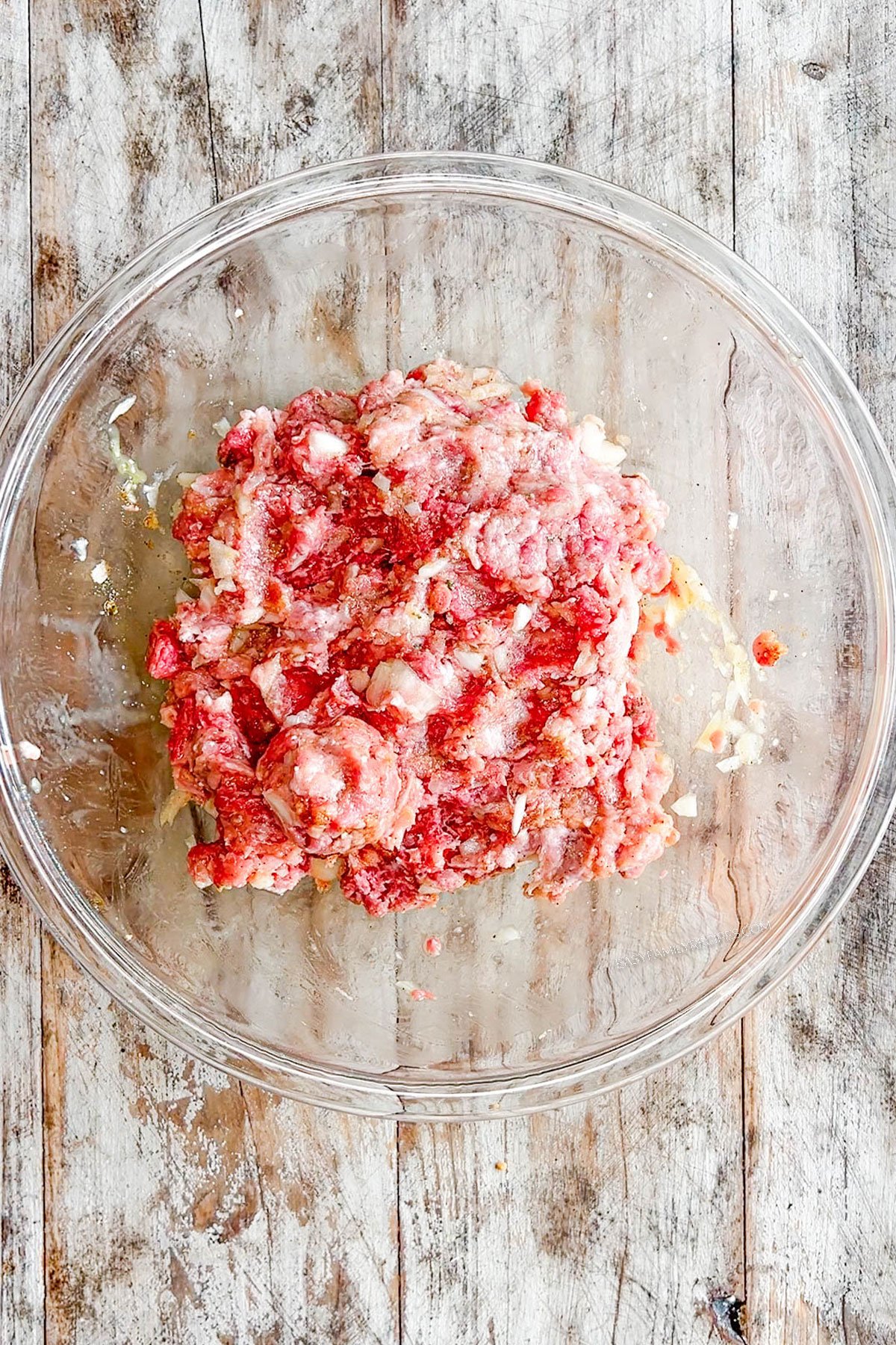 Step 2 for how to make Chili Cheese Meatball Bake - mix together the ground beef and ground pork plus additional ingredients