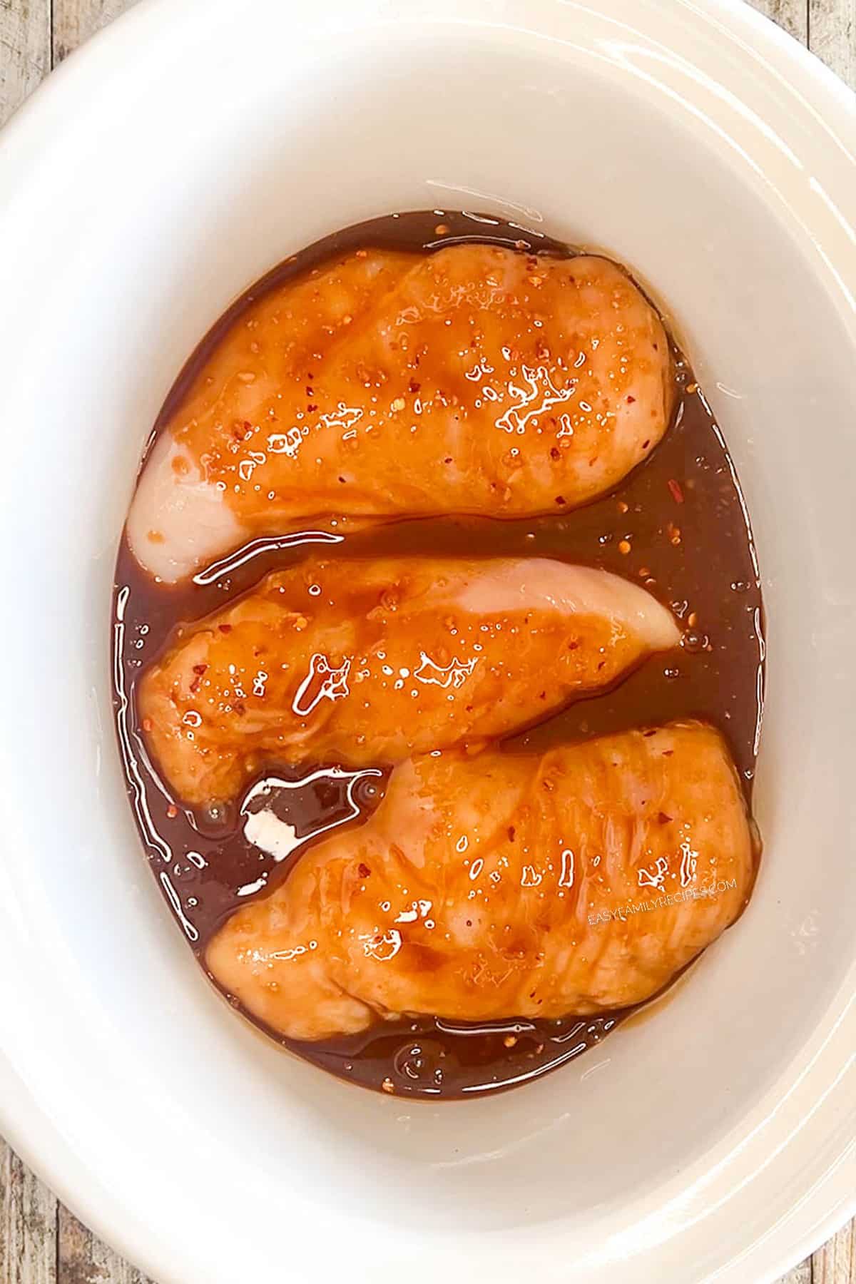 Step 3 for how to make Bourbon Chicken: Add the chicken to the slow cooker and pour the sauce over the top.