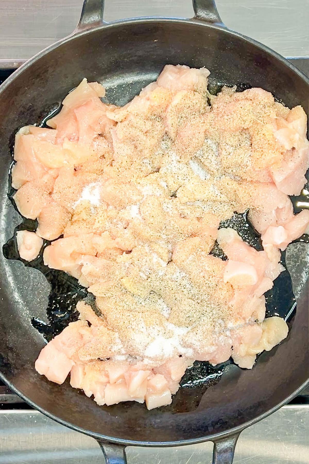 Chicken and seasonings in a skillet before cooking.