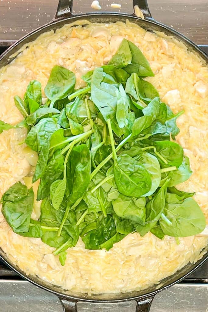 Fresh spinach added on top of skillet.