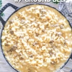 Top view of a cast-iron pan full of loaded mac and cheese. The text reads, “Ground Beef Mac & Cheese”
