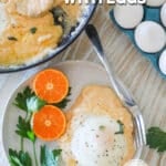 Top view of a white plate full of a serving of cheesy grits with eggs and an orange. Eggs are in the background. The text reads, "Cheesy Grits with Eggs"