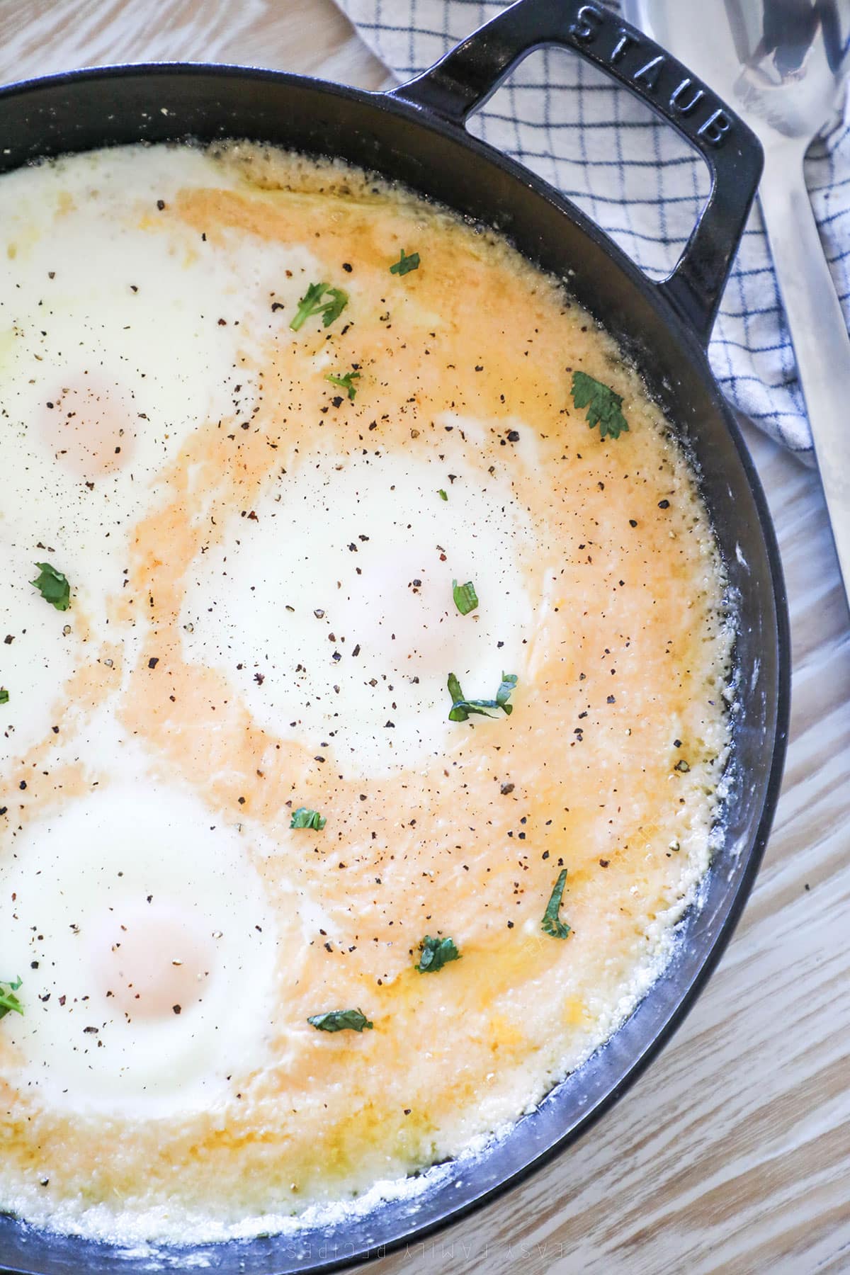 A castiron pan full of cheesy grits with eggs. 