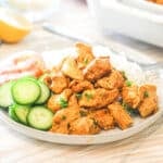 White plate full of chicken schwarma bites with cucumber.