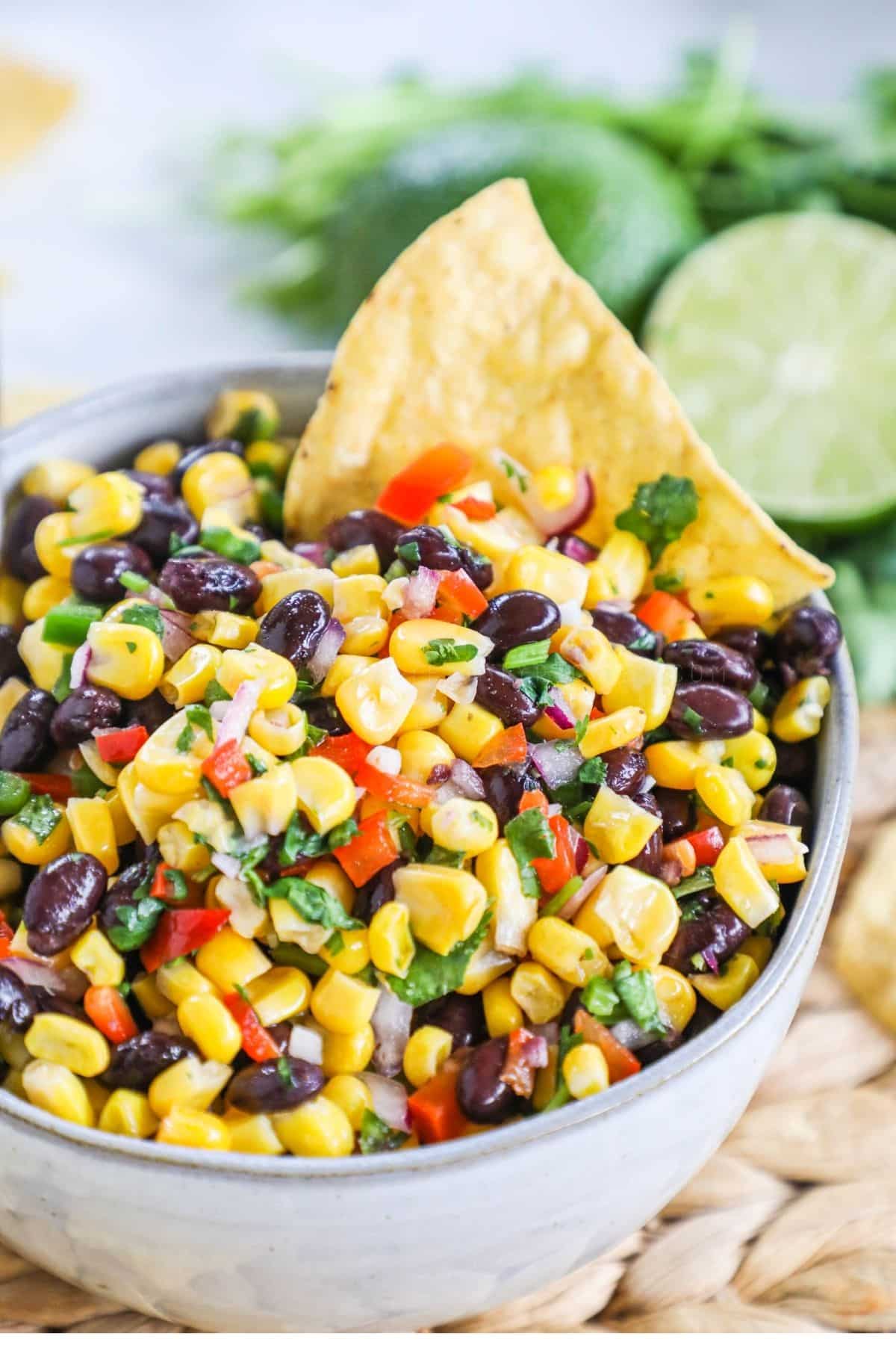 black bean and corn salsa in a white bowl with a single tortilla chip