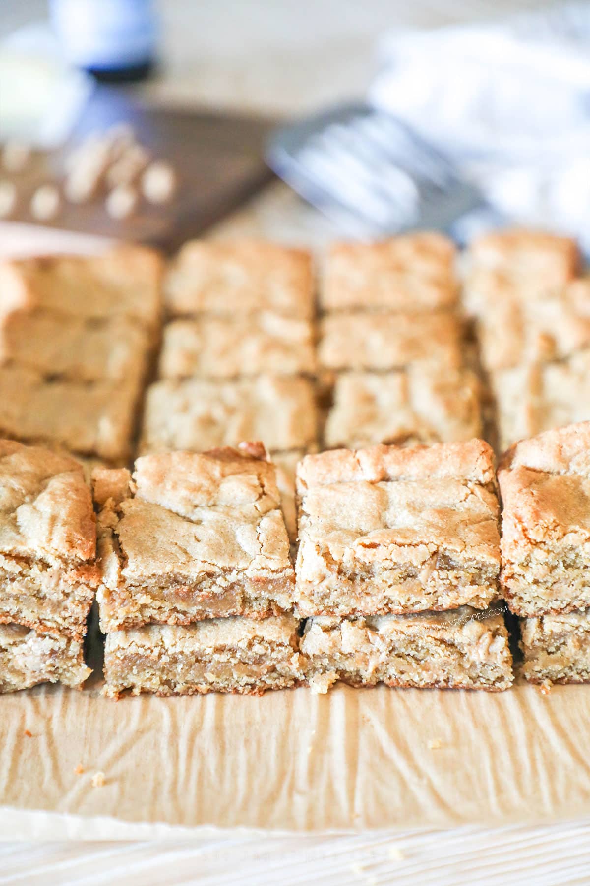 side view of peanut butter blondies layered on top of a cutting board.