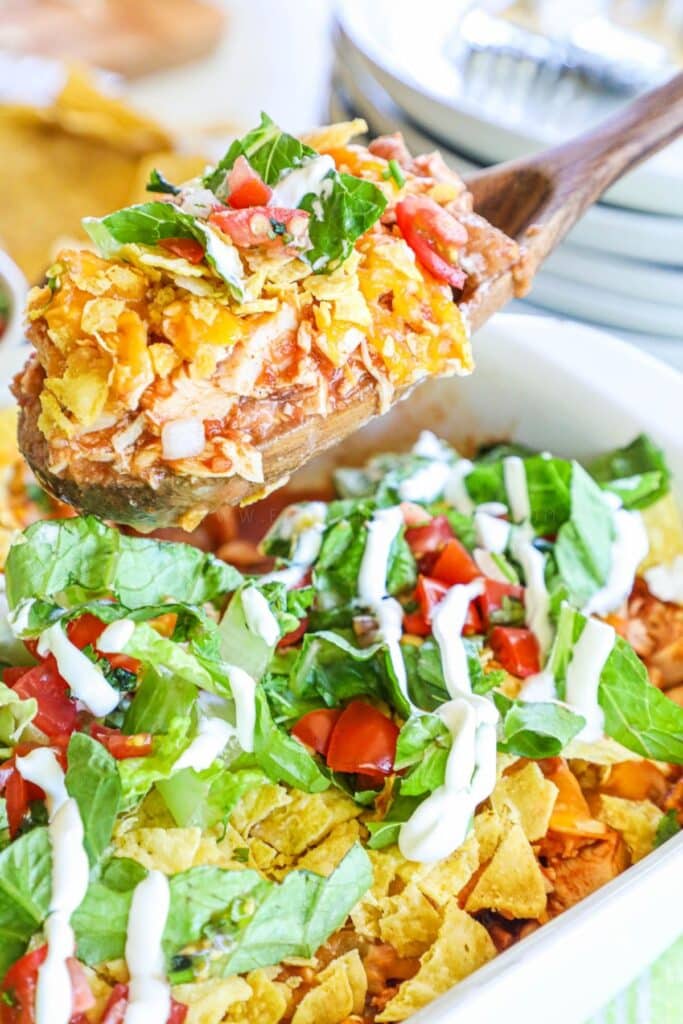 a scoop of chicken taco casserole being lifted from a casserole dish in a spoon