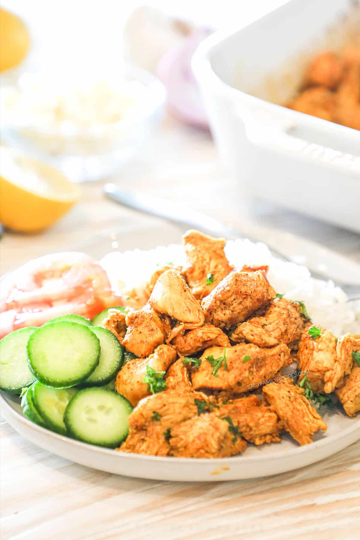 White plate full of chicken schwarma bites with cucumber.
