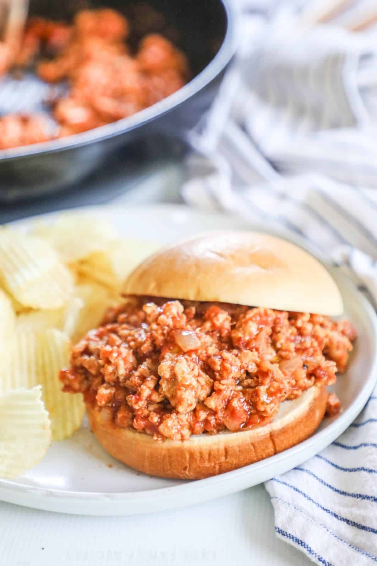 ground chicken sloppy joe on a bun on a plate with potato chips