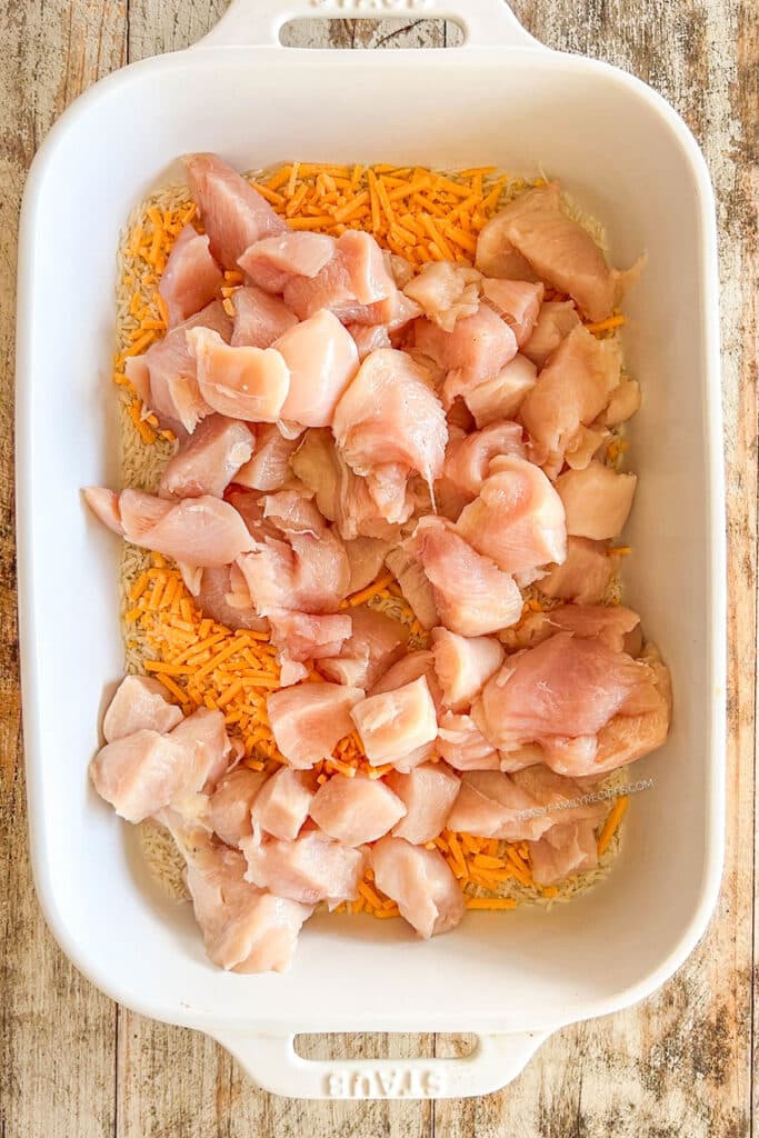 rice and chunks of raw chicken in a casserole dish.