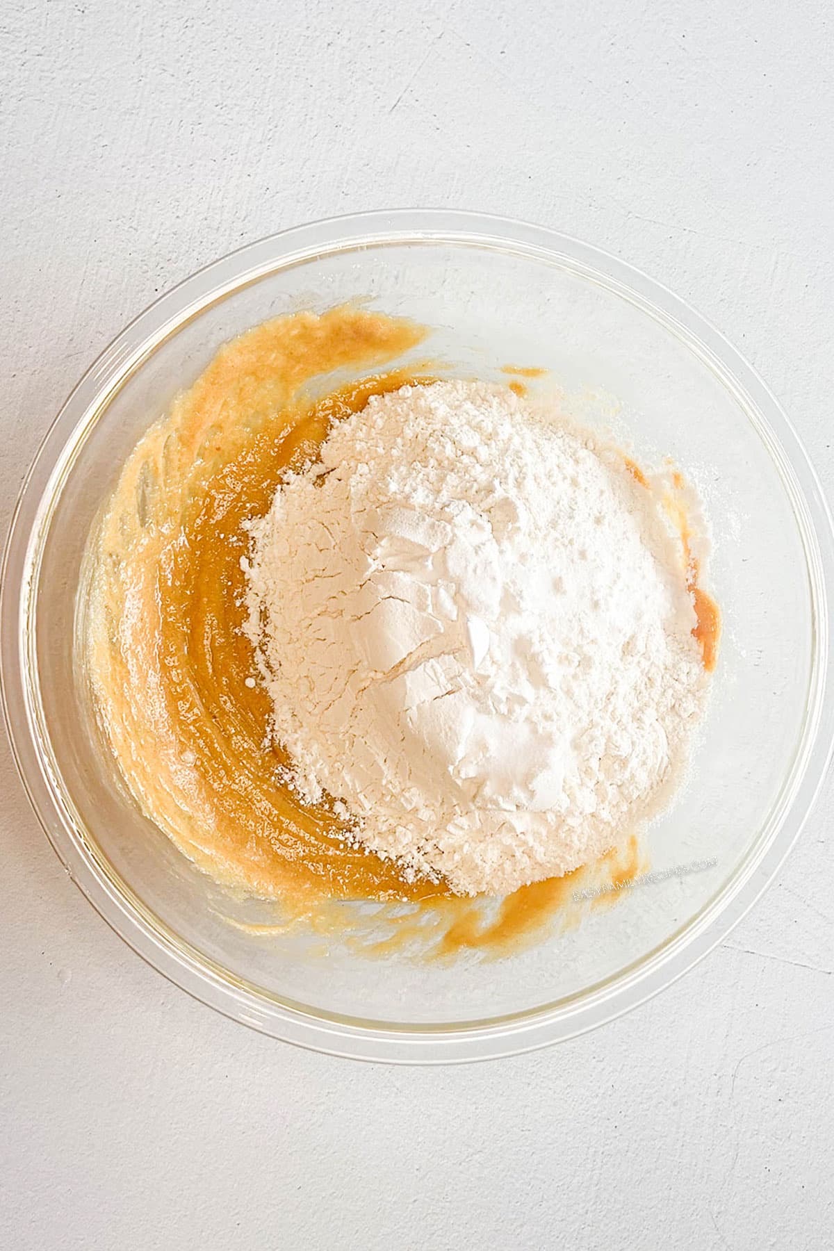 dry ingredients on top of wet ingredients in a mixing bowl.