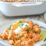 a scoop of rice and chicken on a plate garnished with sour cream, cilantro, and lime wedges.