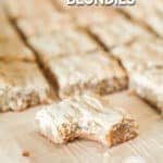 sliced blondies on a cutting board, one in the forefront with a bite taken out.