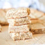 sliced peanut butter blondies on a cutting board, one in the front with a bite taken out.