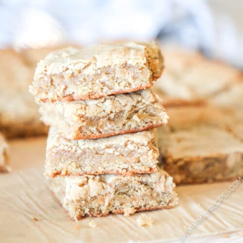 sliced peanut butter blondies on a cutting board, one in the front with a bite taken out.