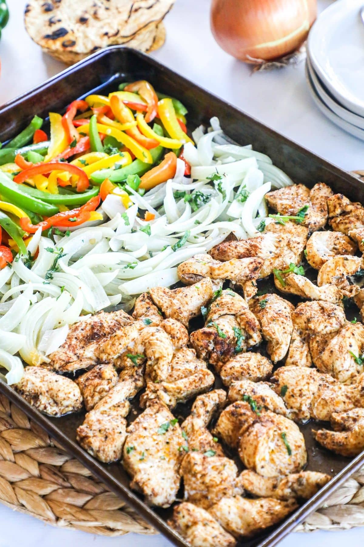 a sheet pan with grilled chicken, onions, and a mix of colored peppers for fajitas