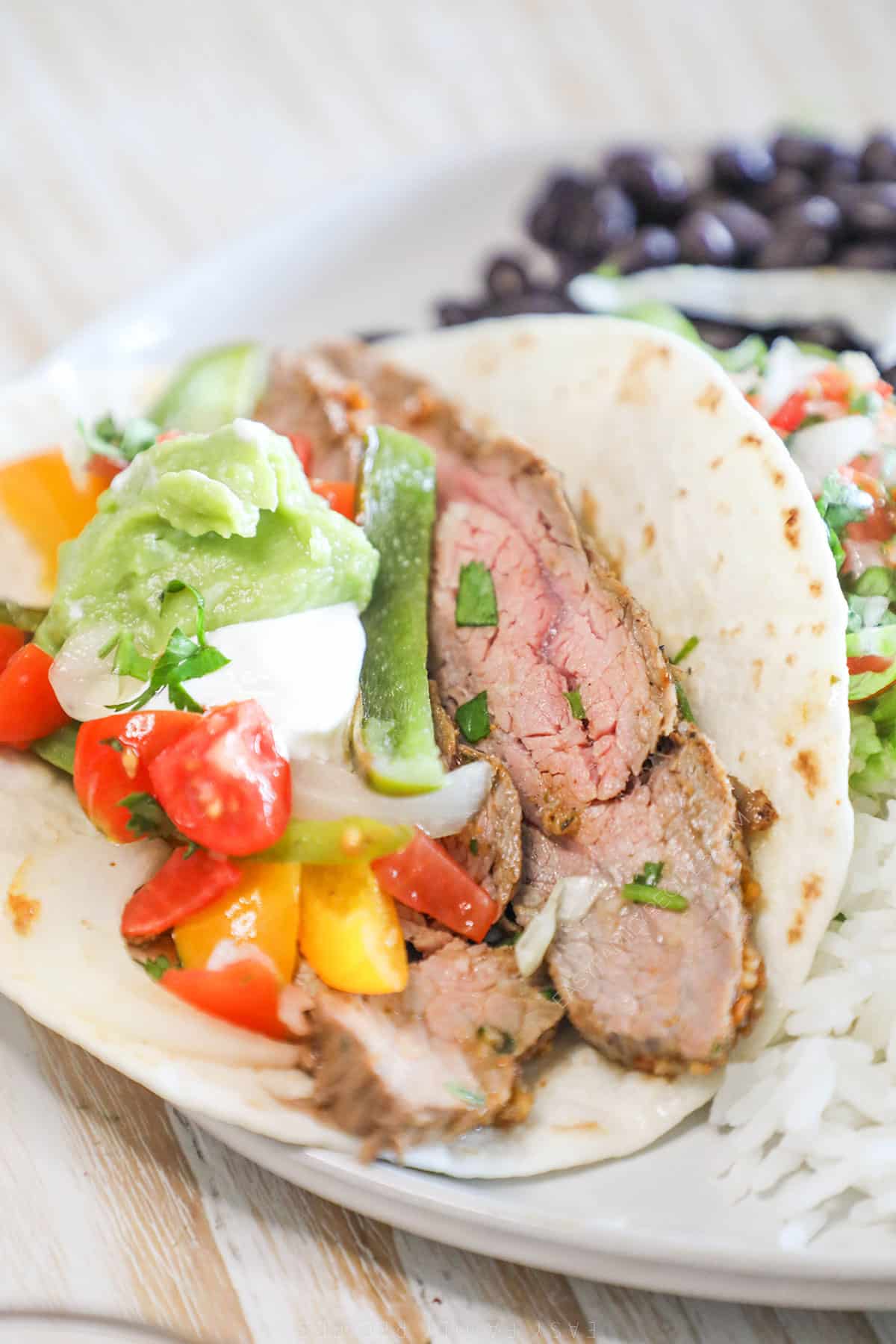 A white plate with a sheet pan steak fajita.