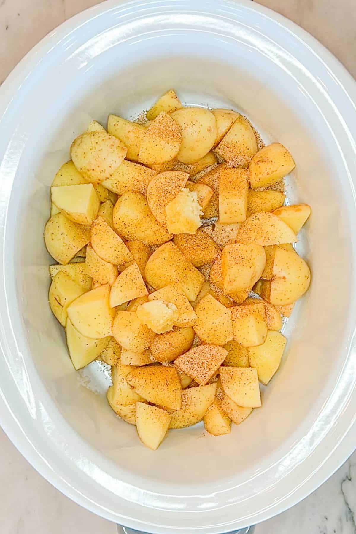 Step one for making Crockpot Sausage and Potatoes - add the potatoes to the Crockpot