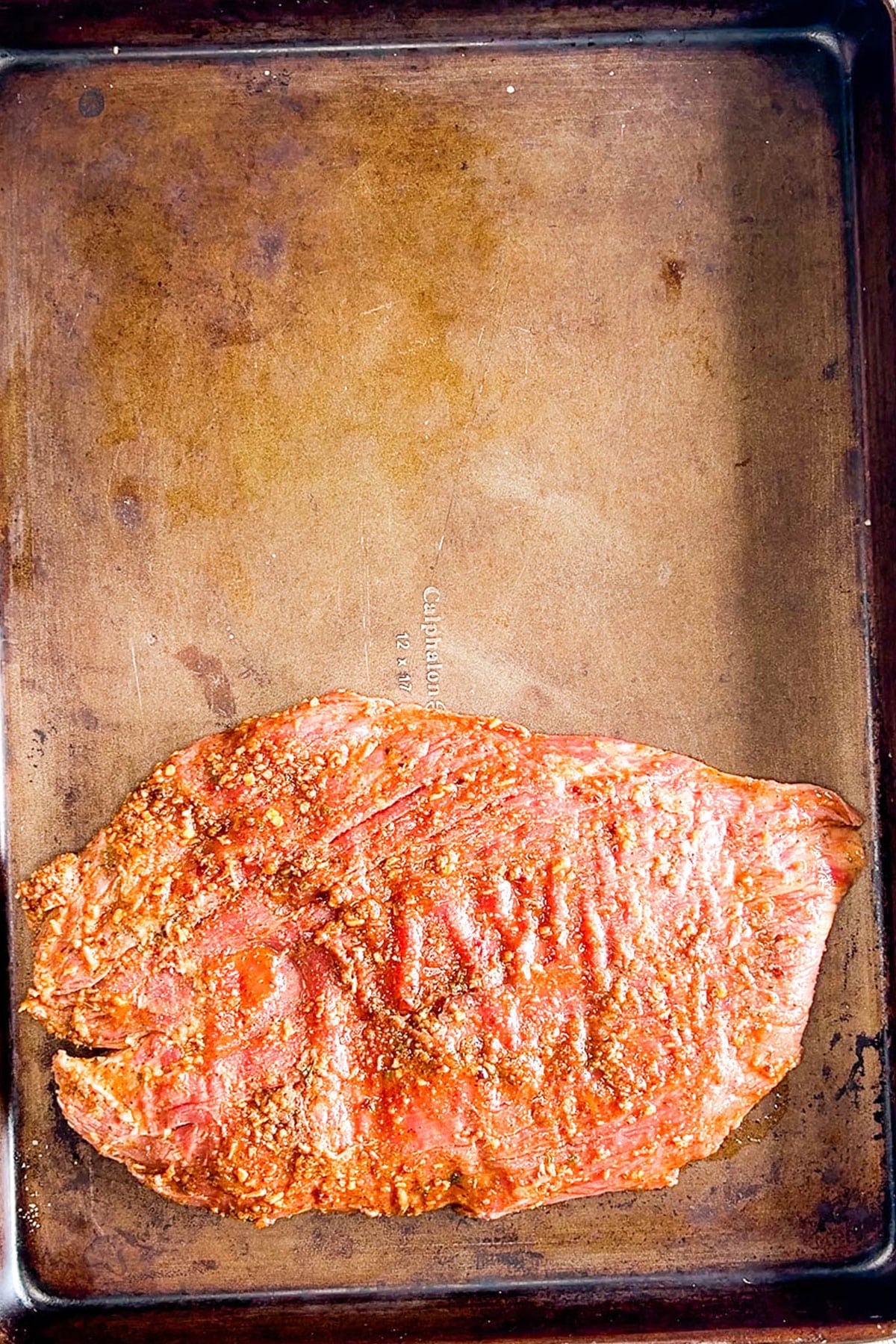 Step 3 of how to make sheet pan steak fajitas: Place the marinated steak on the sheet pan.