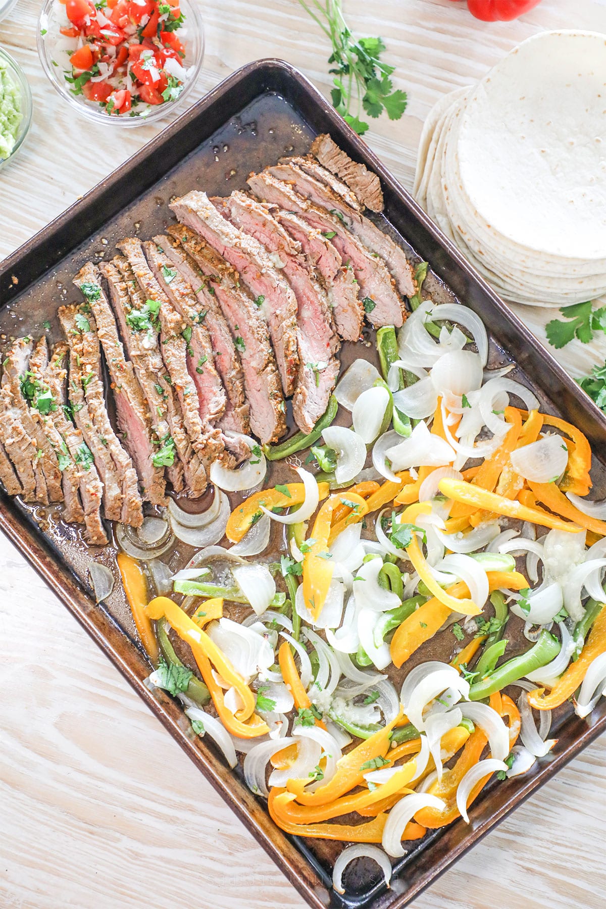 Top view of Sheet Pan Steak Fajitas - a metal cookie sheet with steak and veggies
