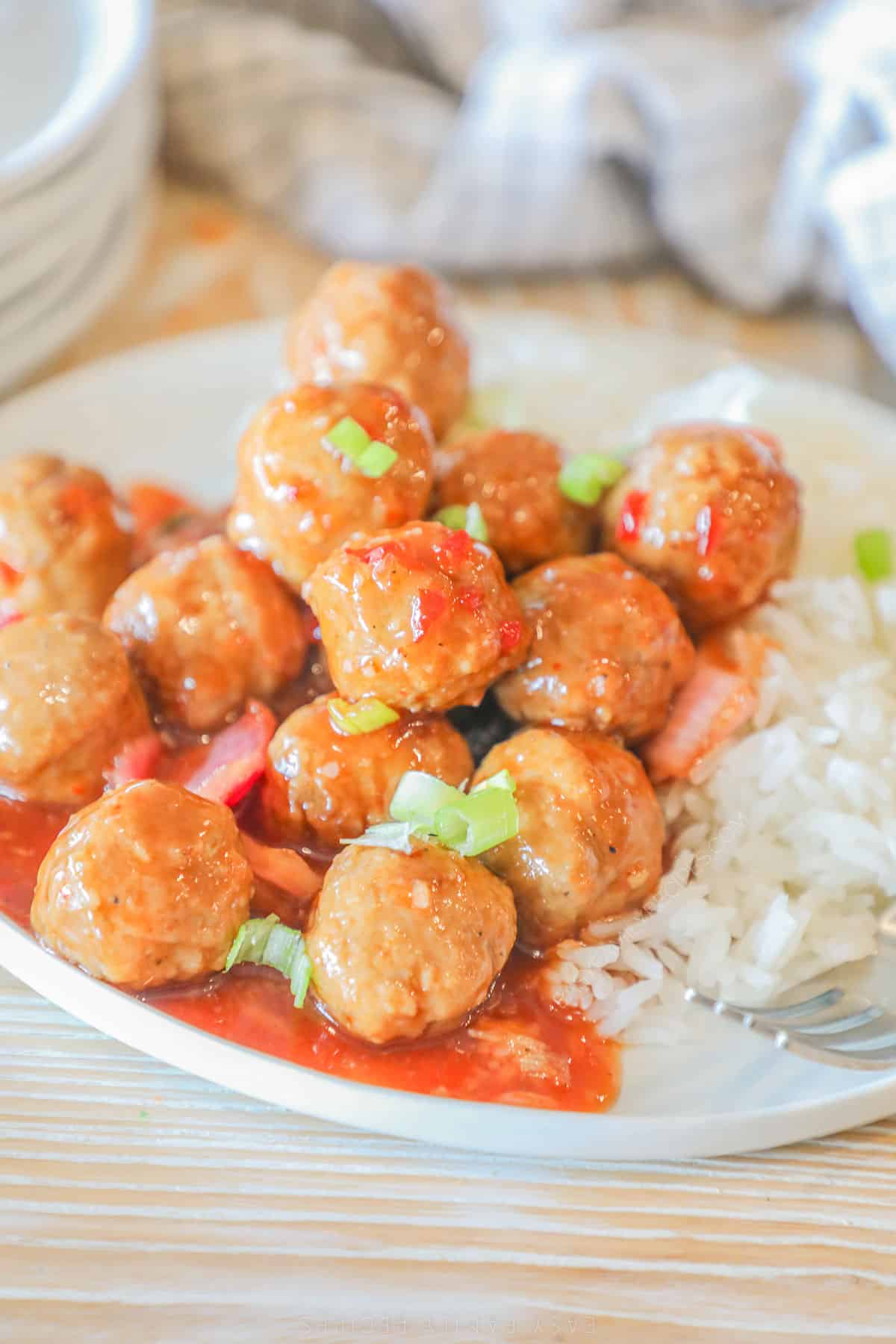 A serving of Crockpot Sweet Chili Meatballs on a white plate with rice on the side