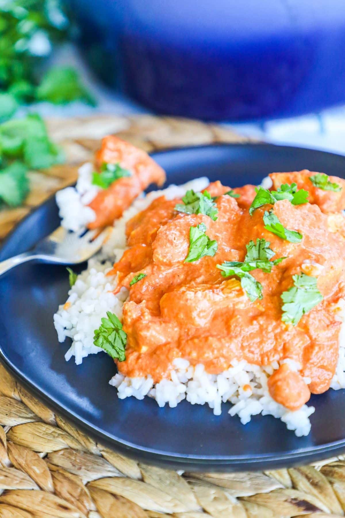 butter chicken served over rice on a blue plate