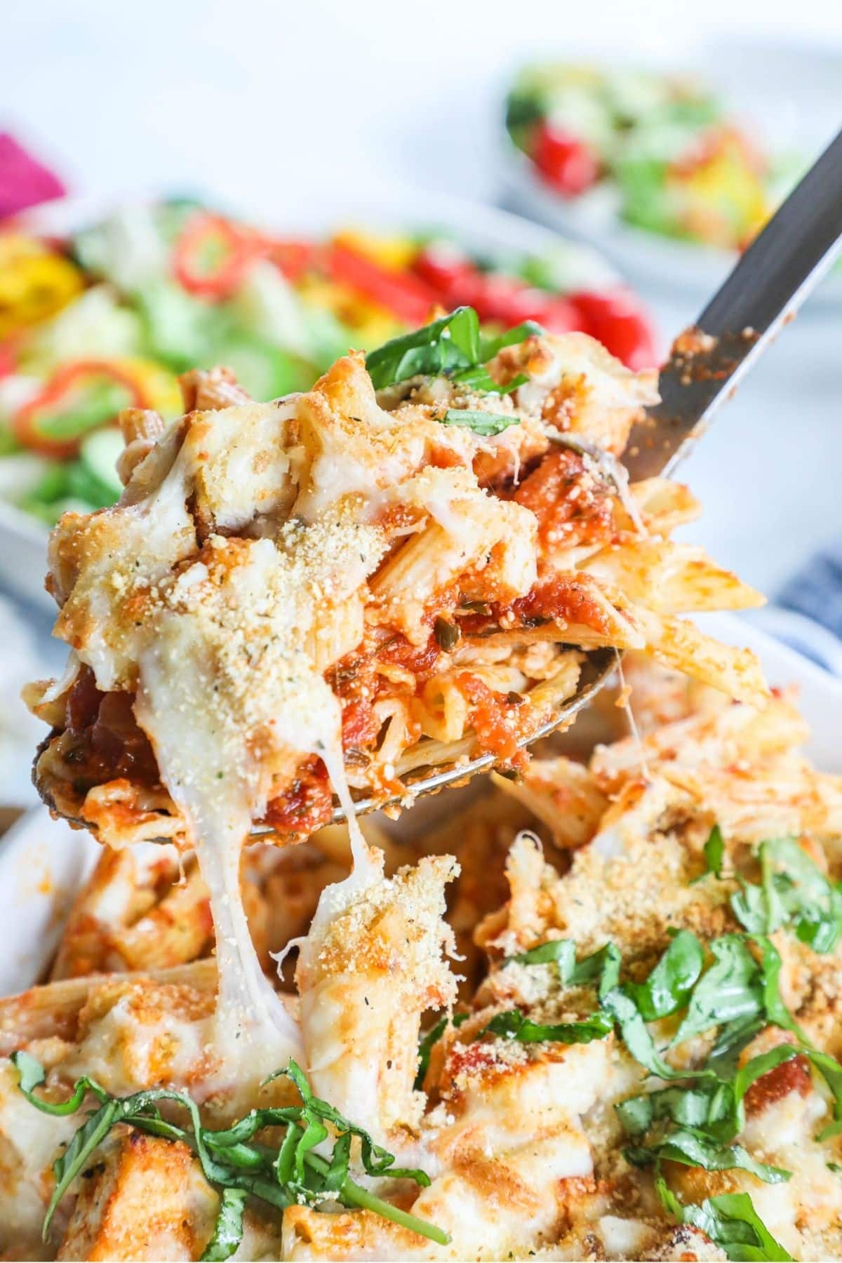 scoop of chicken parmesan casserole being lifted from casserole dish