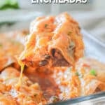 a portion of cheesy enchiladas being lifted out of a baking dish.