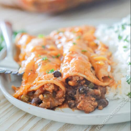 side view of two enchiladas on a plate with rice.