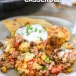 A serving of cowboy casserole with sour cream and cilantro on a white plate. The text reads, “Cowboy Casserole”