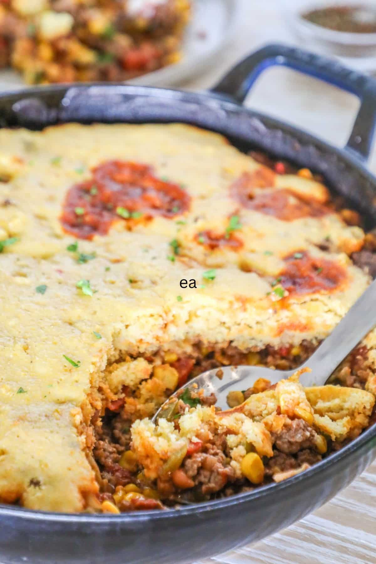 cowboy casserole in a skillet with a spoon scooping out a spoonful