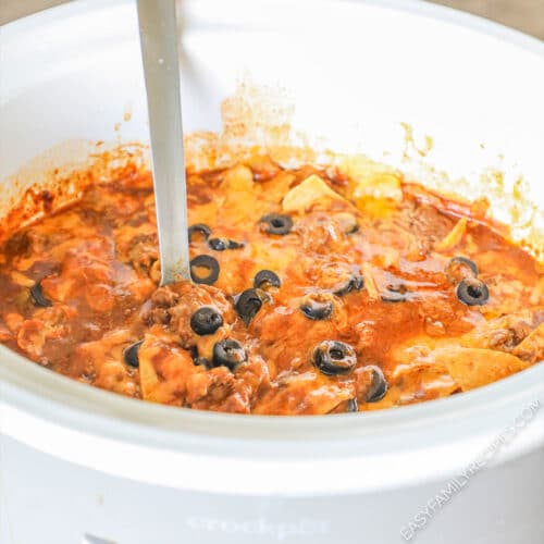 side view of a crockpot of finished beef enchilada casserole.