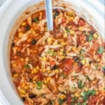 Crockpot Chicken Taco Soup in a white Crockpot with a silver serving spoon
