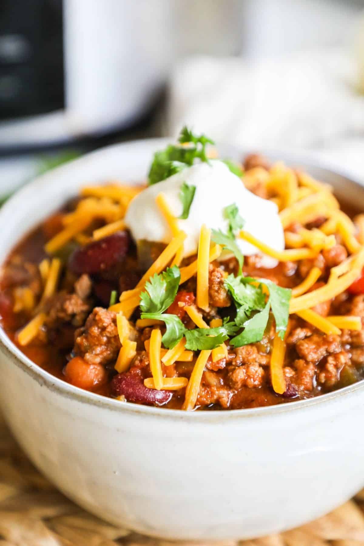 bowl of chili topped with cheese, sour cream, and cilantro