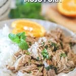 A serving of mojo pork in a white bowl with rice, orange slice, and mint. The text reads, “Crockpot Cuban-Style Mojo Pork”