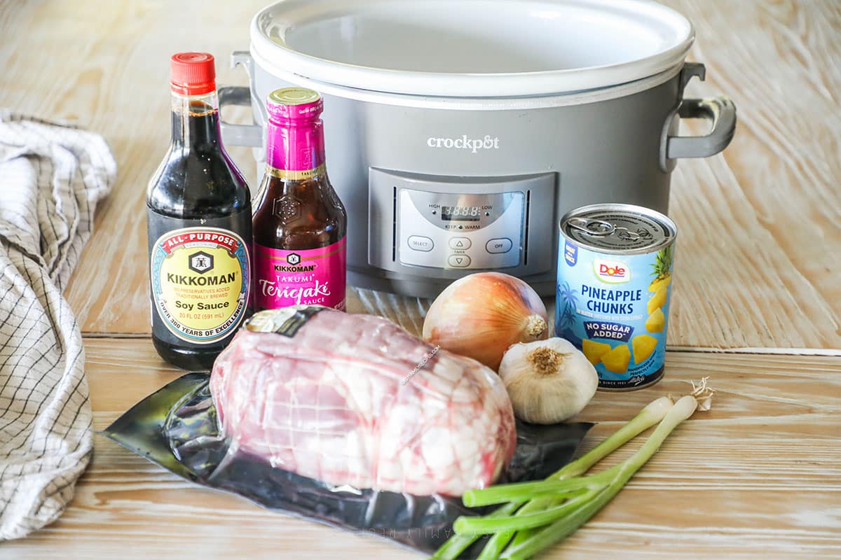 Ingredients needed to make slow cooker pineapple pork sitting in front of a crockpot.
