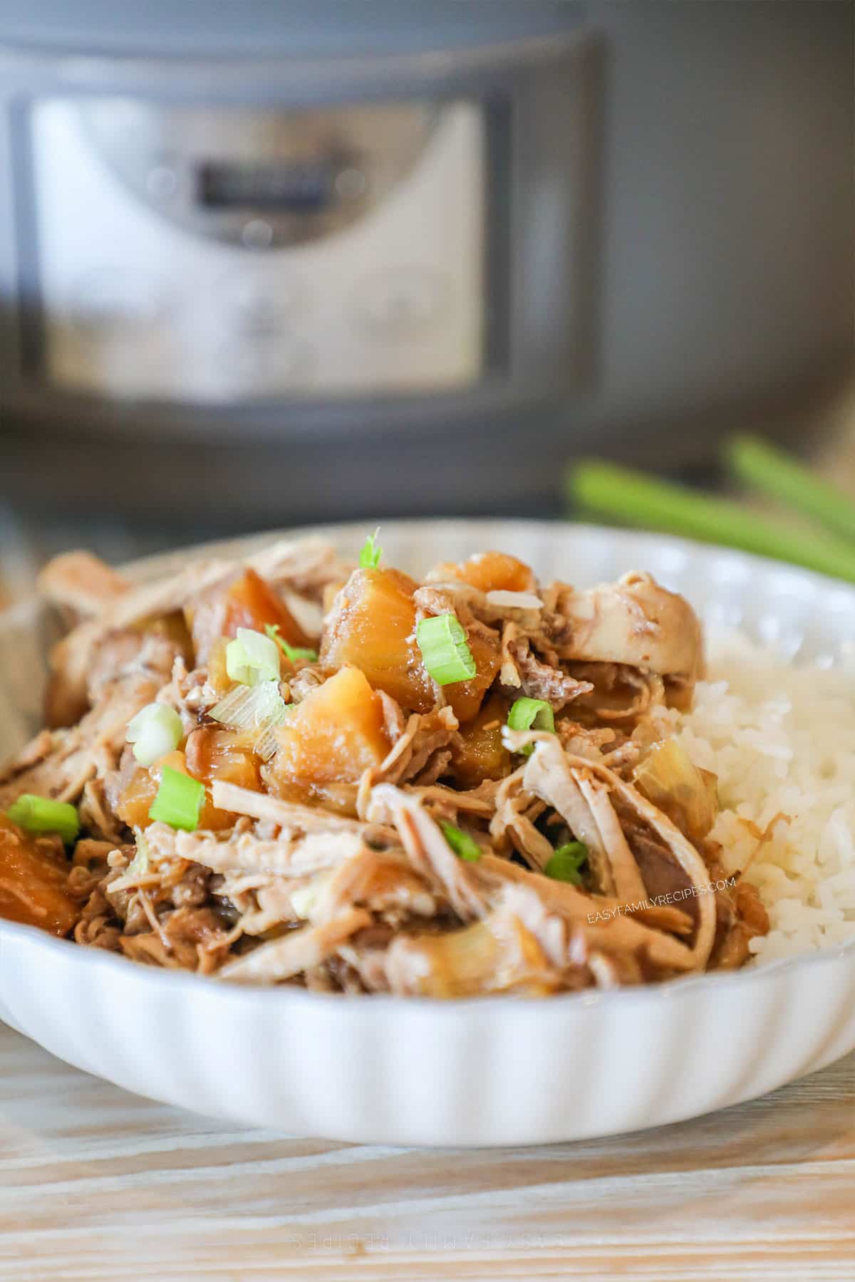 Portion of crockpot pineapple pork served in a white bowl on a bed of rice.
