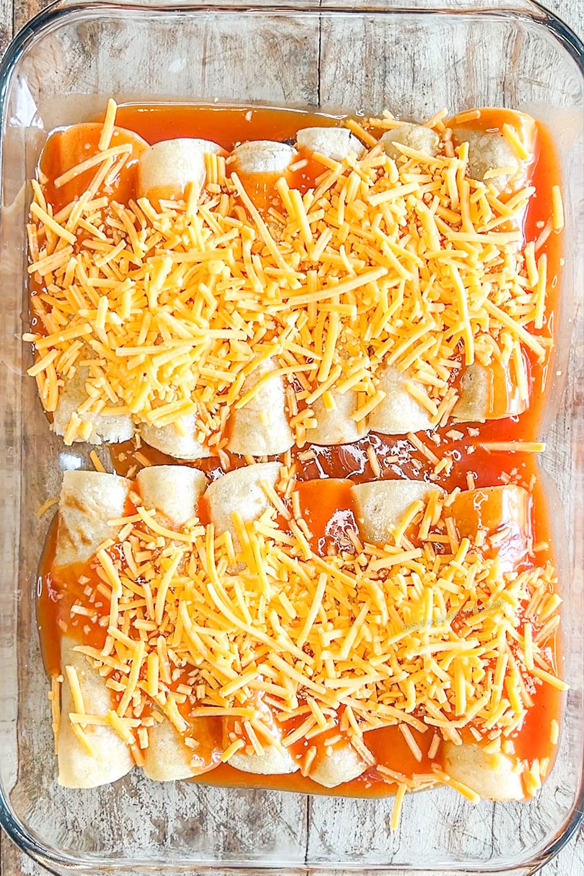 unbaked enchiladas topped with cheese.