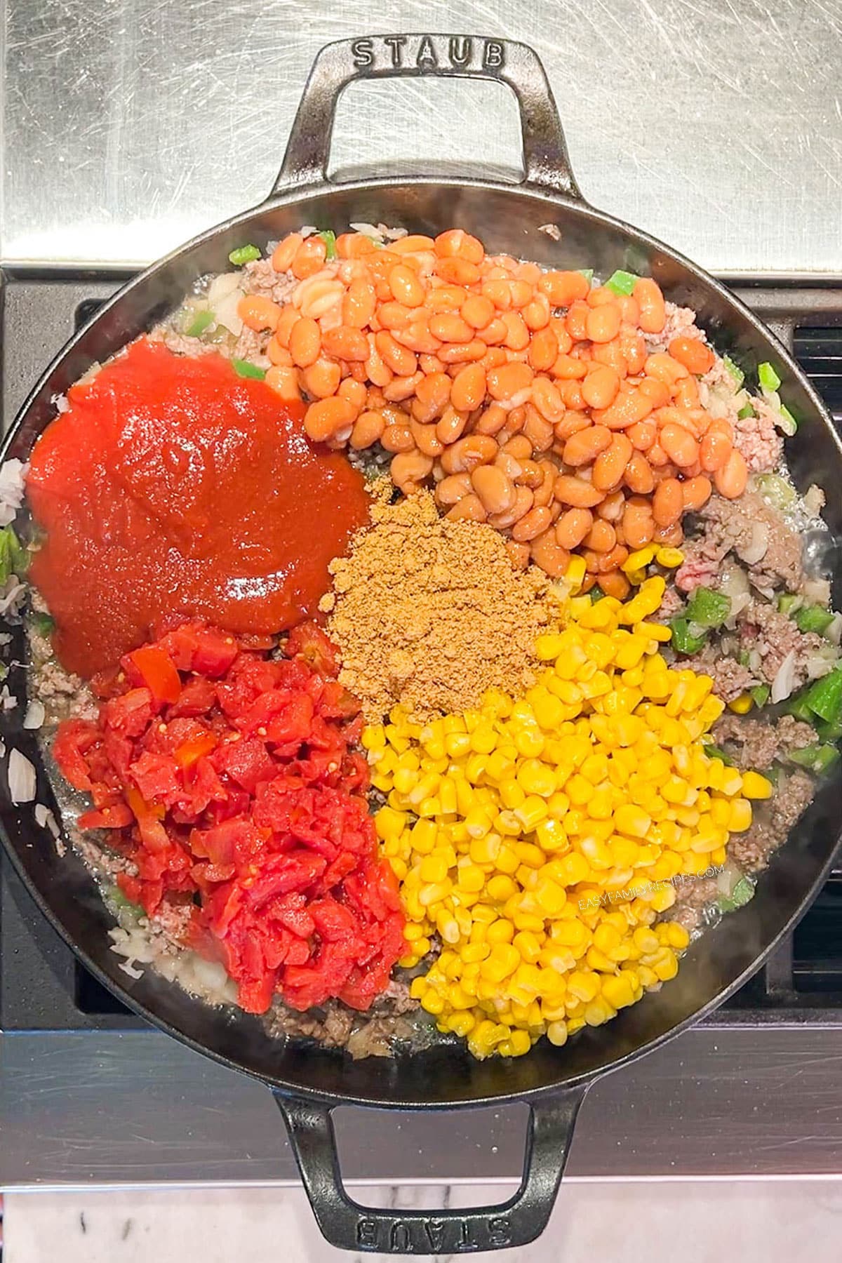 Step 2 of how to make Cowboy Casserole - add the beans, corn, rotel, tomato sauce, and seasoning
