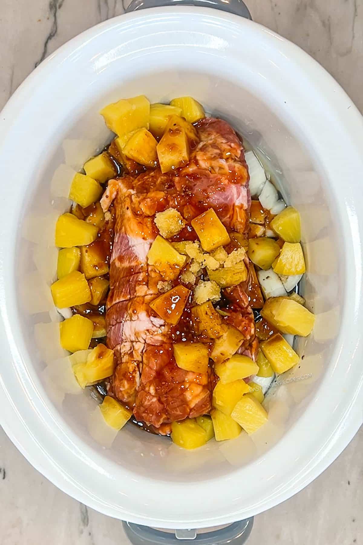 Sauces poured on top of the pork shoulder, onions and pineapple chunks.